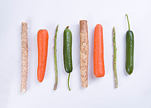 新鲜的蔬菜,山药,胡萝卜,黄瓜和芦笋排列在白色的背景上