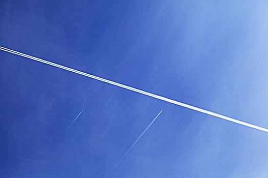 飞机喷气形成的白线在蓝天下划过
