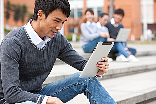 年轻大学生在校园里使用平板电脑