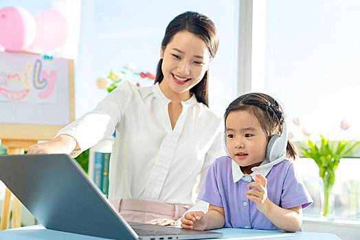老师和小女孩一起使用电脑