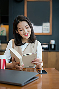 年轻女子在餐厅看书