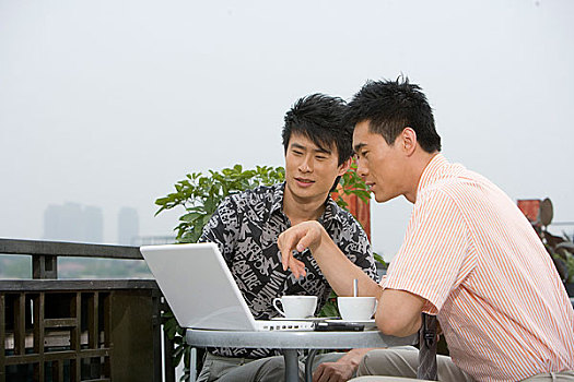 两位年轻的先生在室外喝着咖啡谈工作
