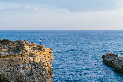 一名亚洲女性站在悬崖边上观赏大海的风景