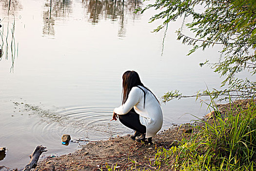 一个女孩蹲在河边