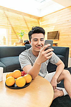 年轻男子坐在沙发边使用手机