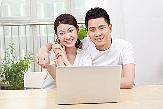 一个青年男人和一个青年女人在窗前看电脑
