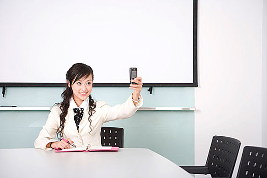 一位女士在坐议桌前用手机拍照