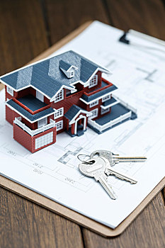 别墅房屋模型,钥匙和图纸放在复古桌面上,房地产概念