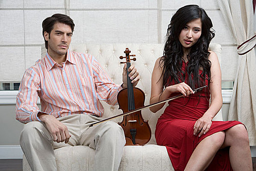 一对男女拿着小提琴坐在沙发上