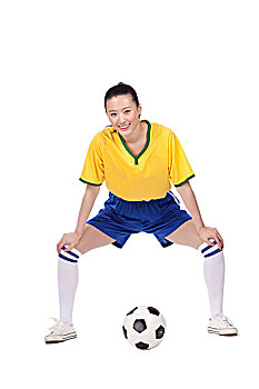 一个穿足球队服拿着足球的女青年