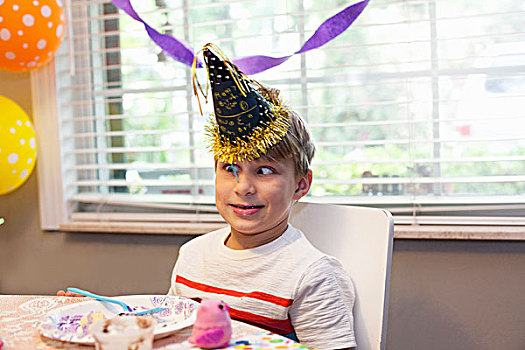 男孩,派对帽,坐,桌子,吃,生日蛋糕,拉拽,鬼脸