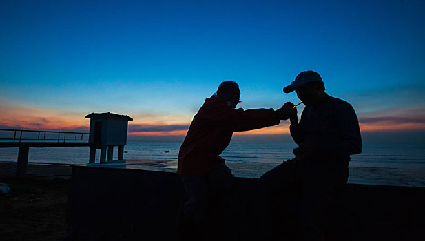 逆光拍摄的沿海渔民