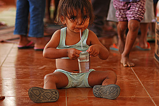 east-timor,timor-leste,dili,plastic,glass,of,water,with,children,in,the,blurred,background