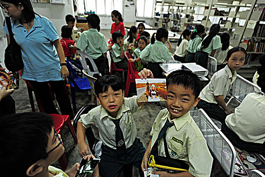 malaysia,kuala,lumpur,children,looking,at,photographs,in,the,classroom