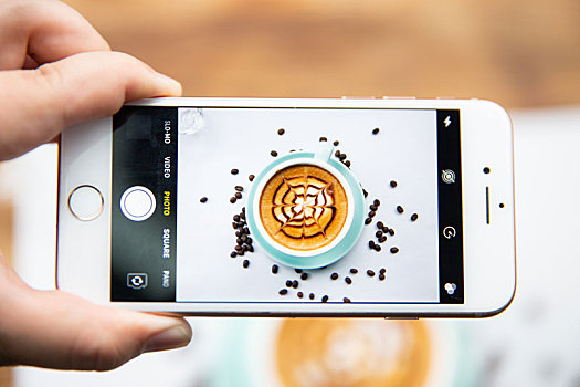 手机摄影透过iphone手机去拍摄一杯卡布奇诺咖啡