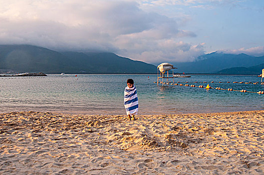 海滩上裹着浴巾的小女孩