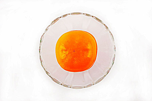 一个透明的玻璃碗盛着柿子