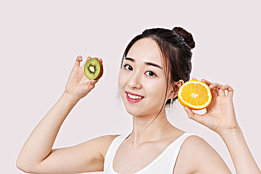 健康饮食,年轻美丽的女性拿着猕猴桃和橙子