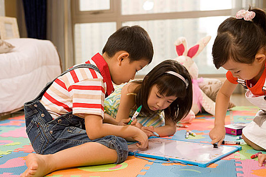 三个小孩趴在地板上画画