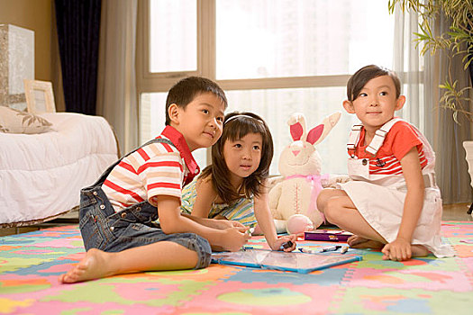 三个小孩在地板上画画