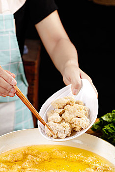 手上端着一盘盐酥鸡和筷子上夹着鸡块