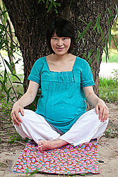 靠在树上练习瑜伽的孕妇