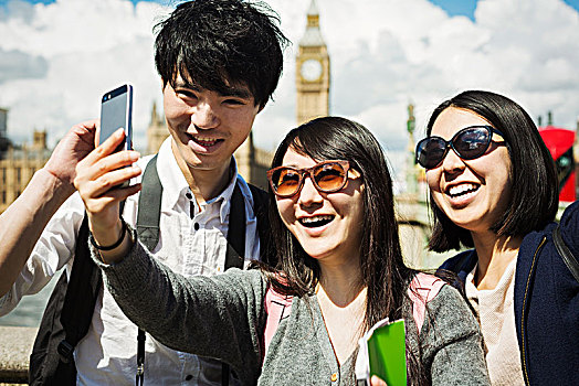 微笑,男人,两个女人,黑发,智能手机,站立,威斯敏斯特桥,上方,泰晤士河,伦敦,议会大厦,大本钟,背景