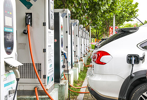 新能源汽车充电站的充电桩和正在充电的汽车