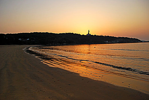 海邊夕陽中的金身觀音像剪影