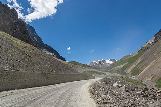 新疆蓝天白云下独库公路高原砂石路汽车背景