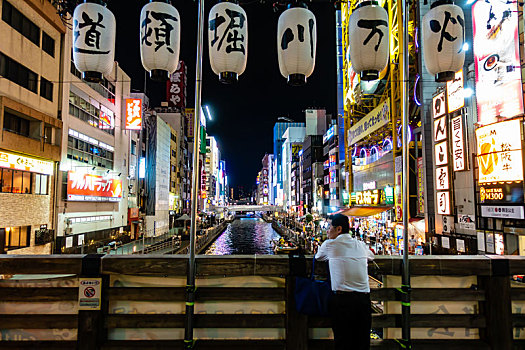 夜晚人们在日本大阪道顿堀川万灯祭的灯笼下欣赏风光