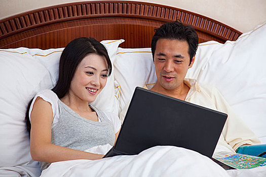 夫妻躺在床上使用电脑