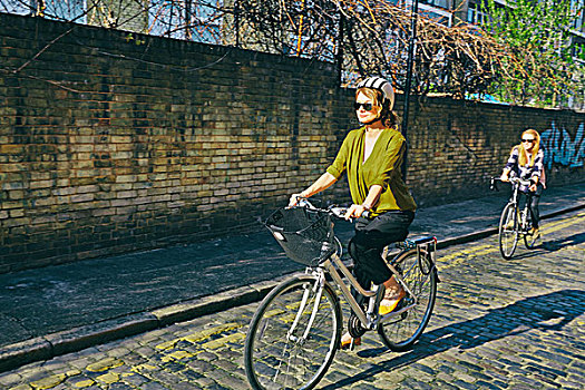 倾斜视角,成年,女人,戴着,墨镜,头盔,骑自行车,鹅卵石,道路