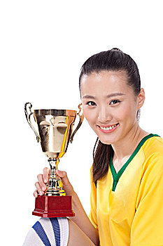 一个穿足球队服拿着奖杯的女青年