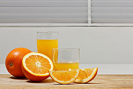 一个完整的橙子和两杯橙汁及切片