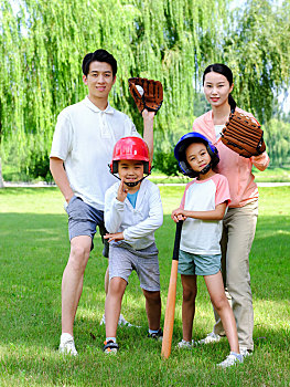快乐的四口之家在公园打棒球