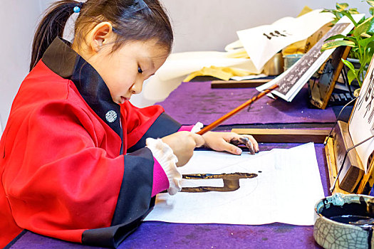穿着红色中式服装练习书法的中国儿童