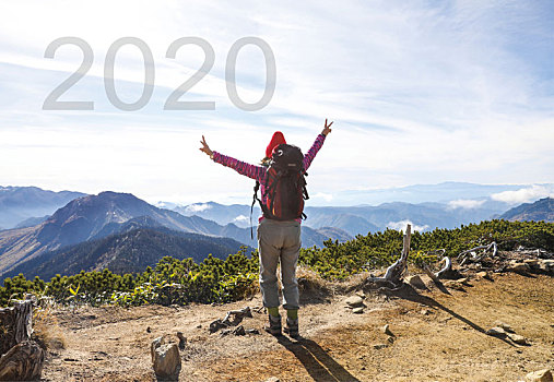 2020数字和女性徒步旅行者在山顶张开双臂合成图像
