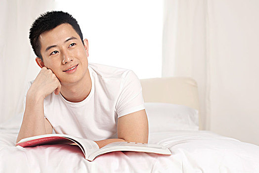 躺在床上看书的青年男性
