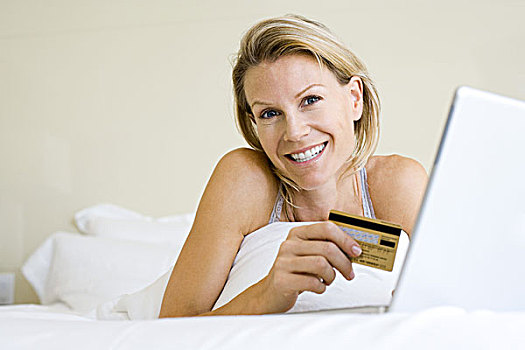 女人,卧,床上,笔记本电脑,拿着,信用卡,看镜头,微笑