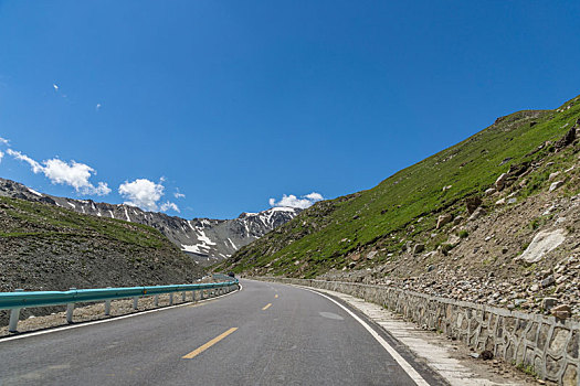 中国新疆夏季蓝天白云下高山草原g217独库公路弯道特写