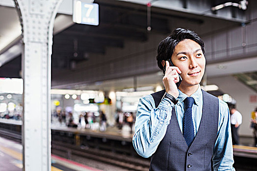 商务人士,穿,蓝衬衫,背心,站立,火车站,站台,交谈,手机