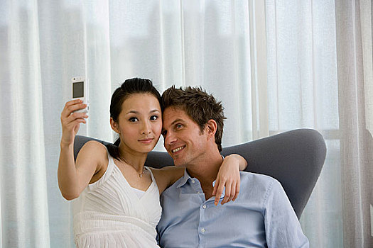 一对夫妻坐在椅子上用手机拍照