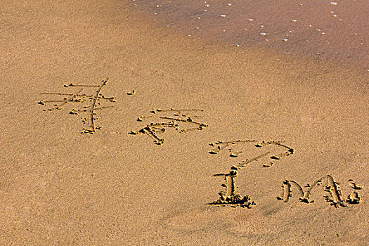 在海滩边黄色细腻海沙上写着,我爱你