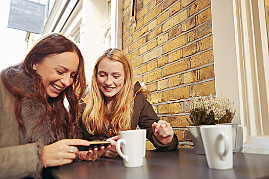 两个,女性朋友,坐,室外,咖啡,看,智能手机