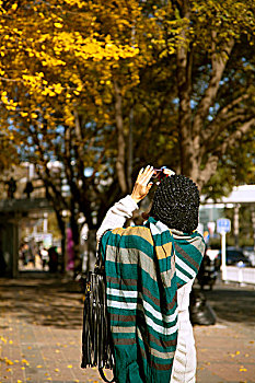 秋天在使馆街拍摄黄色银杏叶的年轻女性