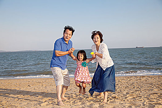 老年夫妻和小女孩在海边玩耍