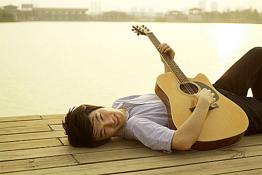 躺在河边弹吉他的年轻男人