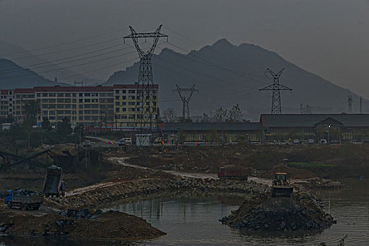 输电塔,房屋,炊烟,截流,拖拉机,汽车,推土机,池塘,河流,两岸,高压线,高压塔,电力,黄昏,清洁能源,绿色电力