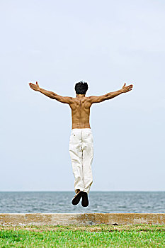 男人,跳跃,空中,海滩,伸展胳膊,后视图